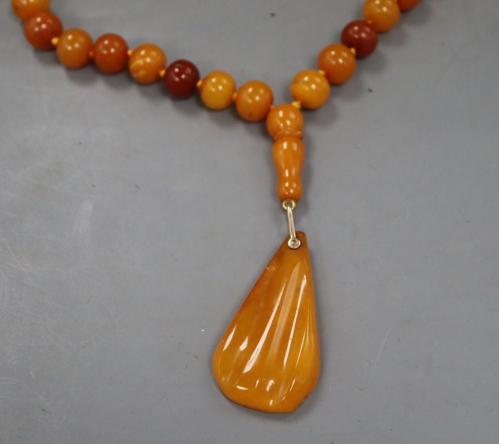 A single strand circular amber bead necklace, with pear shaped amber pendant, gross 74 grams.